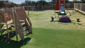A playground with various play structures, including a slide and climbing frames, on artificial grass. - Duplex Le Philandra - 2-4 pers - jacuzzi  (Monteils)