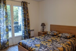 A bedroom with a bed, curtains, a nightstand, and a lamp. - Duplex Le Philandra - 2-4 people - Jacuzzi (Monteils)