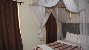 A bed with a canopy, a brown curtain, and a plain wall. - Roof Galaxy Hotel (Machakos)