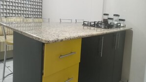 Una cocina con encimera de granito, estufa a gas y un armario amarillo.