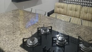 Una cocina con encimera de granito, cocina a gas, televisor montado en un estante negro y un papel tapiz detrás del sofá.