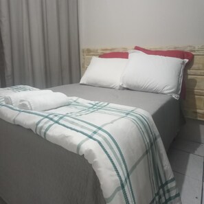 A bed with a white and green checkered blanket, a red pillow, and a white pillow. - Elegante Apartamento centro de Curitiba (Curitiba)