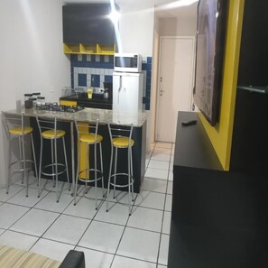 A compact kitchen with a central island, four bar stools, a microwave, and a refrigerator. - Elegante Apartamento centro de Curitiba (Curitiba)
