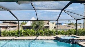 A swimming pool with a tiled border and a small hot tub area, surrounded by a covered patio with a metal frame.