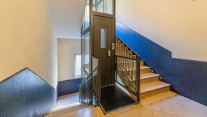 A staircase with a metal railing, a glass door, and a blue accent wall. - Panacea (Salerno)