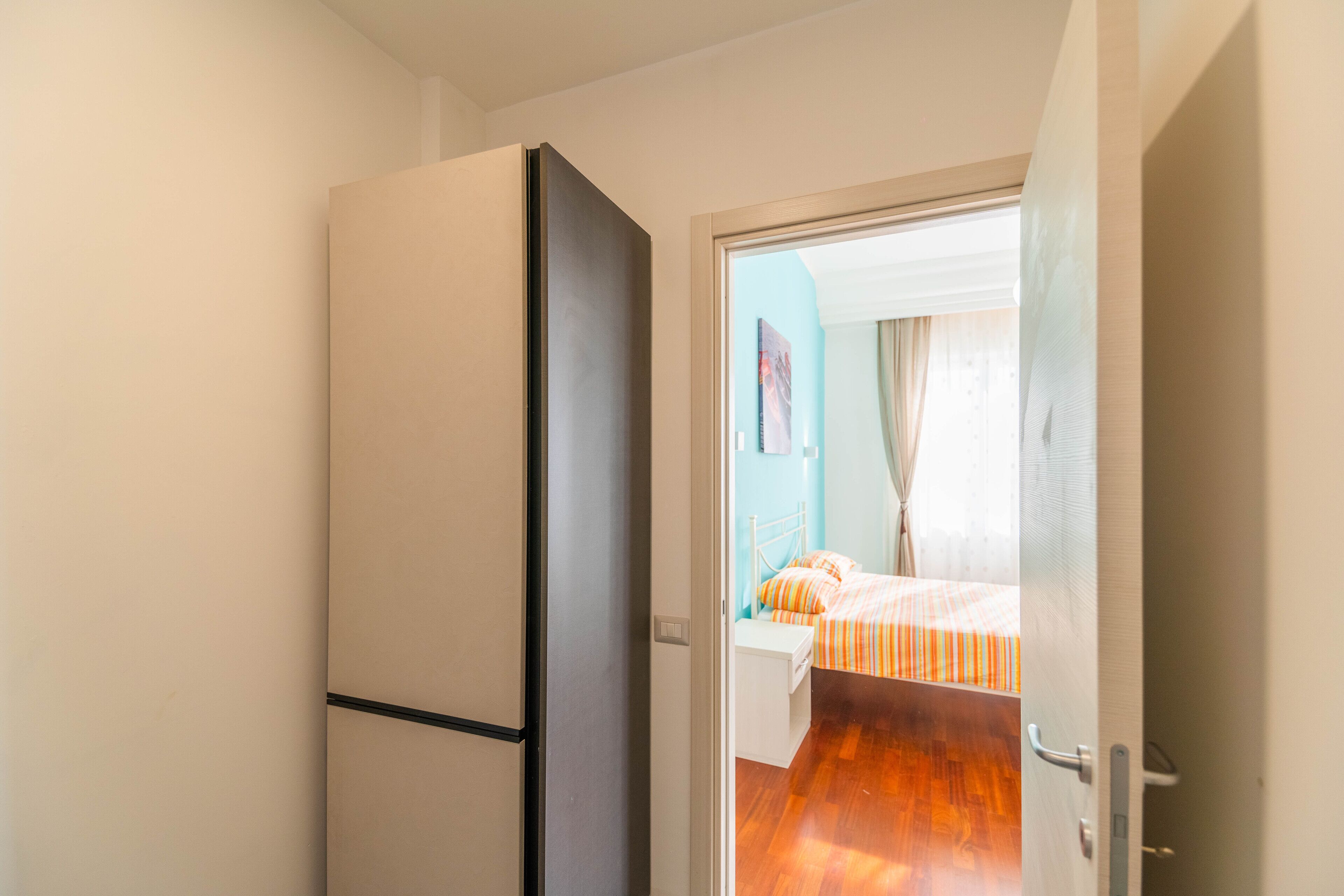 Una habitación de hotel con cama, un armario y una puerta que da a otra habitación.