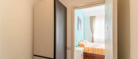 Una habitación de hotel con cama, un armario y una puerta que da a otra habitación.