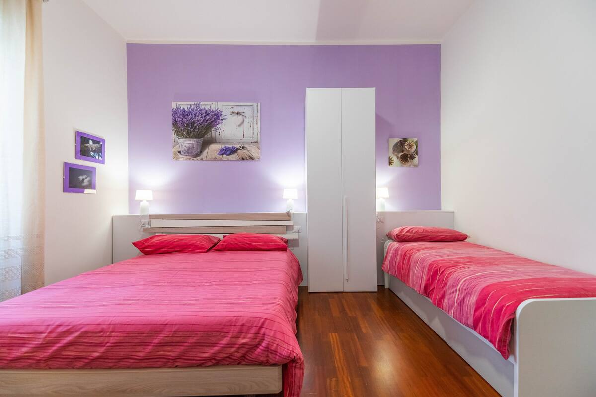 A bedroom with two single beds, a wardrobe, and a wall-mounted mirror.