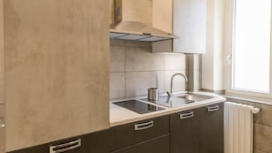 A modern kitchen with dark cabinets, a stainless steel sink, and a window providing natural light. - Panacea (Salerno)