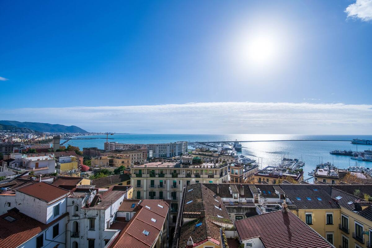 A coastal cityscape with historic buildings, a marina, and a clear sky.