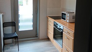 Een kleine keuken met een magnetron, oven en houten kastjes.