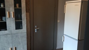 Een keuken met een grijs kastje, een witte koelkast en een houten vloer.