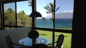 Une pièce avec vue sur l’océan, une table avec des chaises et une lampe suspendue.