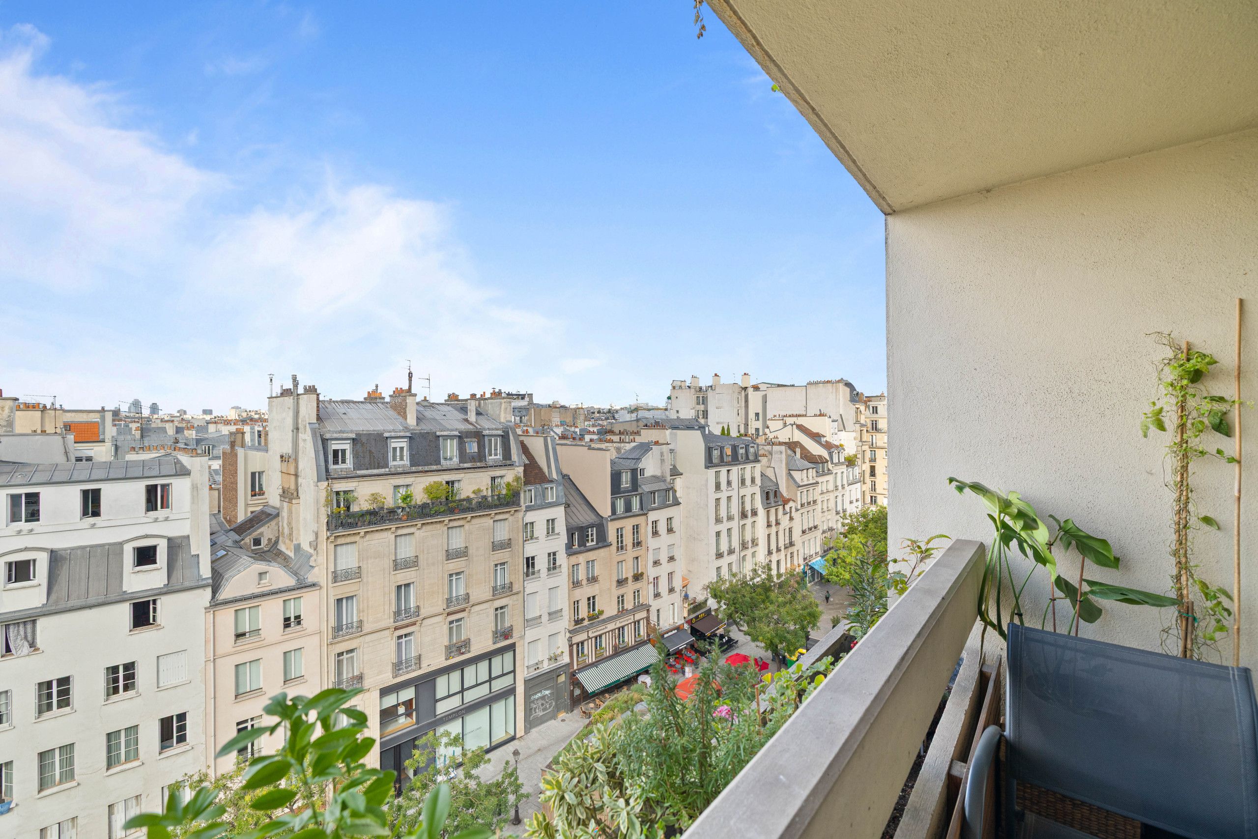 A balcony with a view of a cityscape, featuring multi-story buildings with various architectural styles.