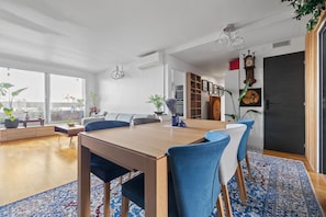 A spacious living area with a dining table, chairs, a sofa, and a large window offering a view. - Attica, 3BR/2BA, 6 people (París)