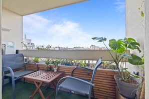 An outdoor seating area with a table and chairs, a potted plant, and a view of the cityscape. - Attica, 3BR/2BA, 6 people (París)