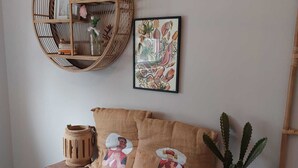 A cozy room with a wooden bench, a woven basket, a framed artwork, and a potted plant. - Bungalow "The Shrimp" close to the beach! Air conditioning! South corner 1 (Renesse)