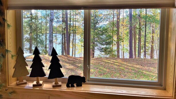 Una ventana con vista a un bosque y tres árboles de Navidad de madera.