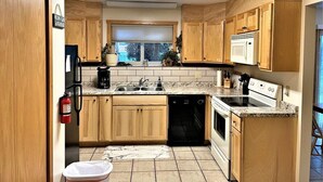 Una cocina con armarios de madera, lavavajillas, estufa y microondas.