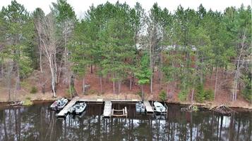 A dock with several boats, surrounded by a forested area with tall trees.