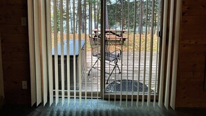 A wooden cabin with a sliding glass door leading to an outdoor patio area. - Red Pines -  Elk Lake Condo #3 (Phillips)