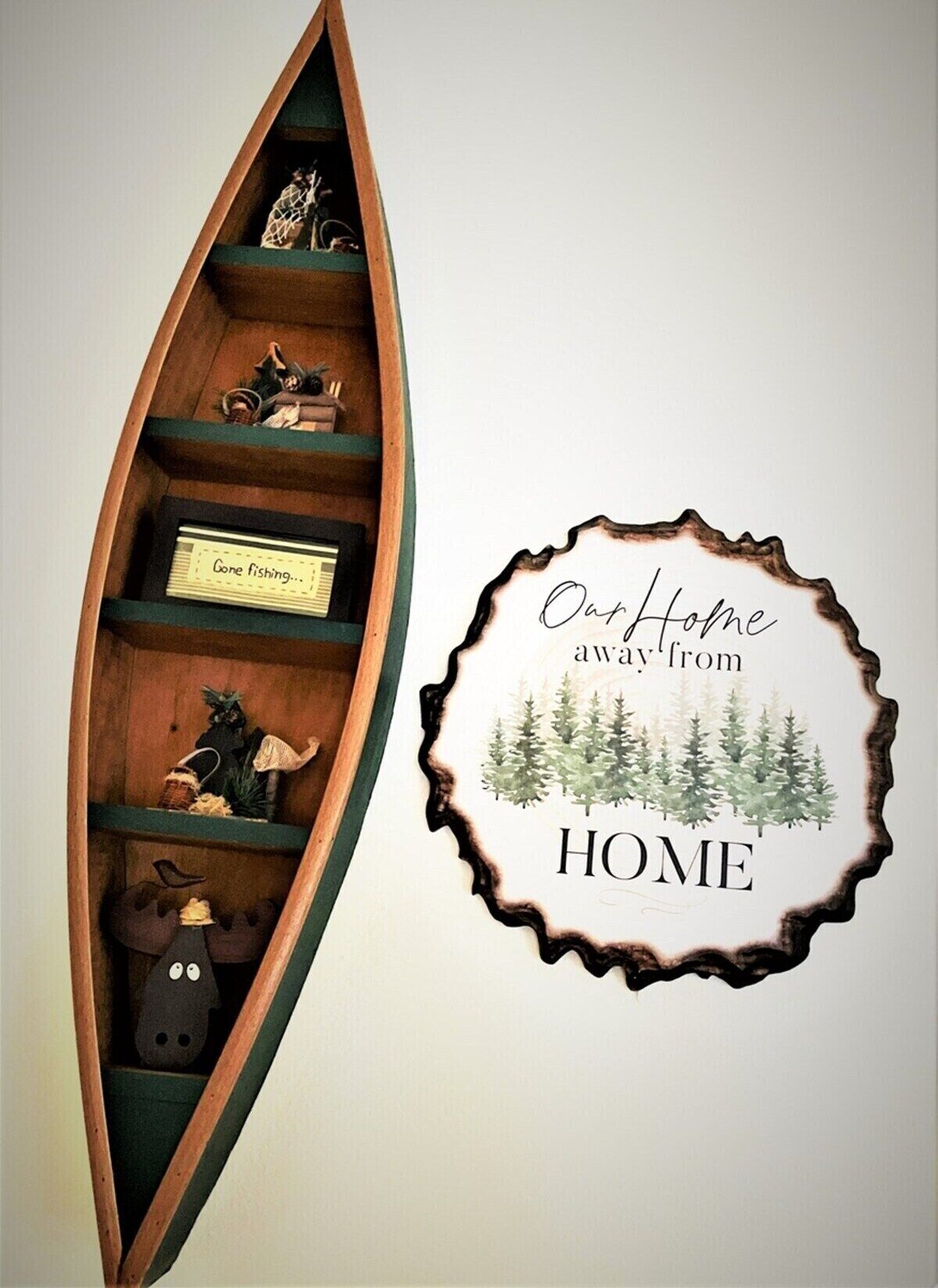 Une étagère en bois en forme de bateau, sur laquelle sont disposés divers objets, et une décoration murale portant l’inscription : « Notre deuxième maison ».