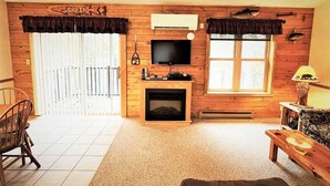 A cabin interior with a fireplace, television, and wooden walls. - Red Pines -  Elk Lake Condo #3 (Phillips)