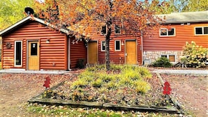 Eine Blockhütte mit Veranda, kleinem Garten und Steinmauer.