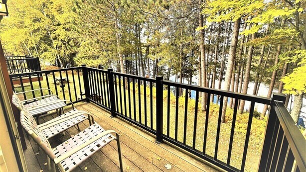 Eine Holzterrasse mit Metallgeländern und zwei Metallstühlen.