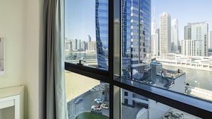 A high-rise hotel room with a view of a city skyline and a river. - The Bay Residences - Canal View (Dubai)