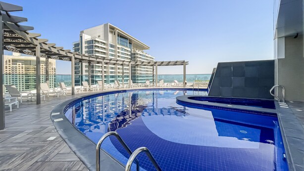 A rooftop pool with a clear view of the city skyline, lounge chairs, and a modern building structure. - The Bay Residences - Canal View (Dubai)