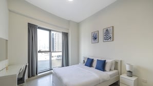 A modern hotel room with a large bed, a desk, and a view of the city through the window. - The Bay Residences - Canal View (Dubai)