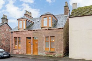 Un bâtiment à deux étages, doté d’une façade en briques, d’une porte d’entrée en bois et d’une baie vitrée.