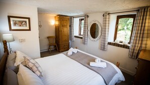Un dormitorio con cama, armario de madera, espejo y ventana con cortinas.
