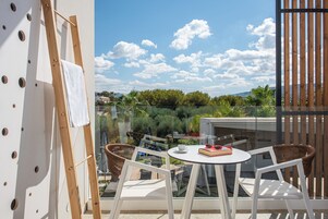 A balcony with a table, chairs, and a view of greenery and buildings.