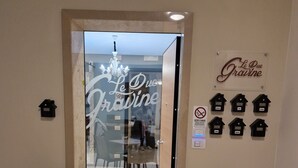 L’entrée d’un hôtel, avec une porte en verre, une enseigne indiquant « Le Due Gravine », et plusieurs panneaux en forme de maison accrochés au mur.