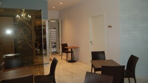 Un espace repas moderne avec des cloisons en verre, un lustre et une porte donnant sur une autre pièce.