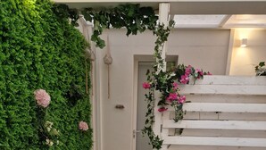 Un espace extérieur accueillant, aménagé avec des tables et des bancs en bois, entouré d’un mur végétal luxuriant et d’une cloison en bois blanc.