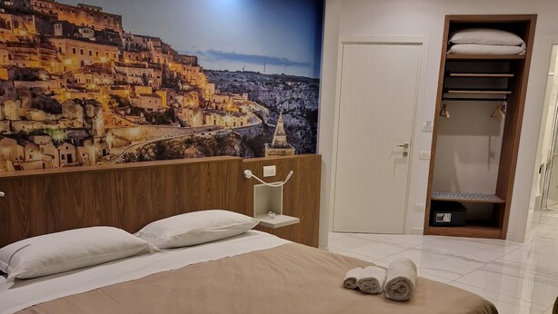 Une chambre d’hôtel avec un grand lit, une armoire et une fresque représentant un paysage urbain.