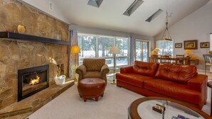 A living room with a stone fireplace, leather sofa, and a glass coffee table. - REDC23 - Spacious Home, Gas Fireplace, Ping Pong (Sunriver)