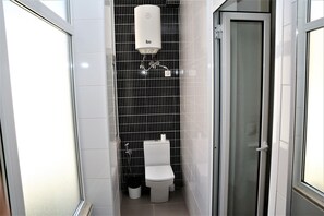 Un bagno moderno e piccolo con un water, un bidet e una doccia.