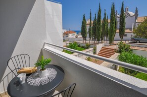 A balcony with a table, chairs, and a potted plant.