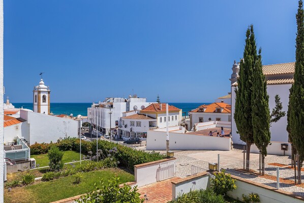 A coastal town with white buildings, a church tower, and a view of the sea.