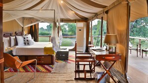 A tented accommodation with a bed, a chair, a desk, and a view of greenery. - The Untamed Bandhavgarh by TUTC (Manpur)