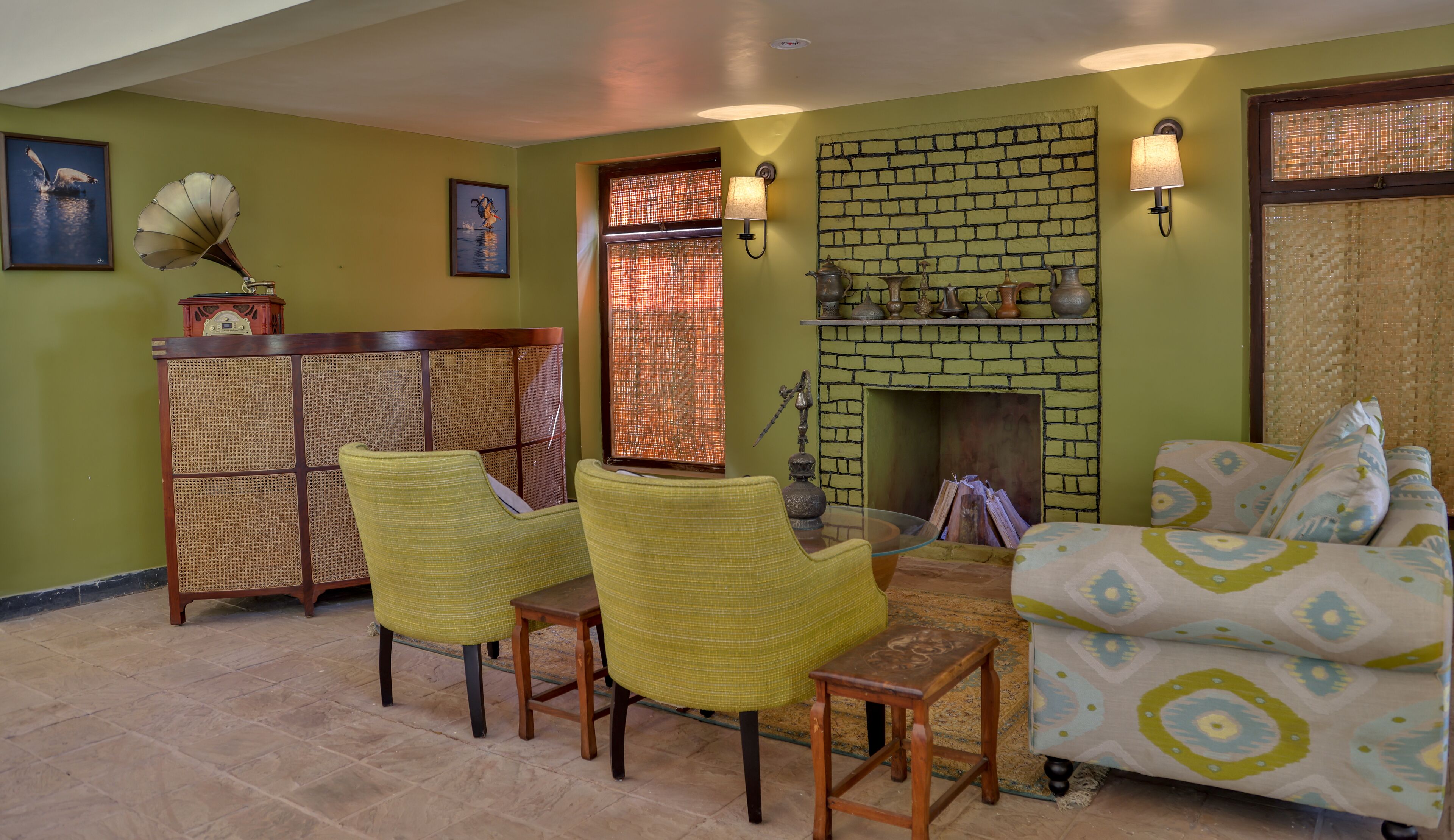 A living room with a brick fireplace, wicker chairs, a sofa, and a gramophone.