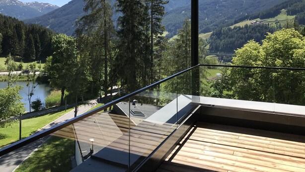 Een balkon met uitzicht op een meer, bos en bergen.