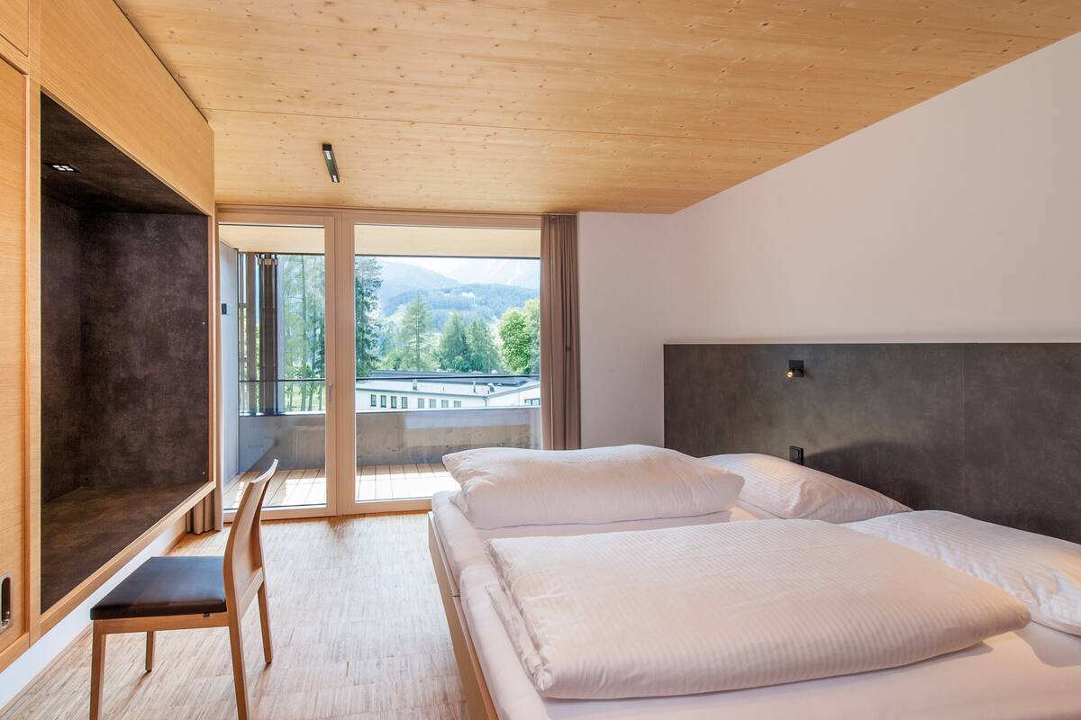 Una habitación de hotel moderna con una cama grande, un escritorio y vistas al exterior.