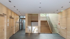 Een modern interieur met een trap, houten wanden en een betegelde vloer.