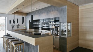 Een moderne keuken met een centraal kookeiland, barstoelen en een geïntegreerde koelkast.