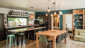 A modern kitchen with a central island, bar stools, and pendant lighting.